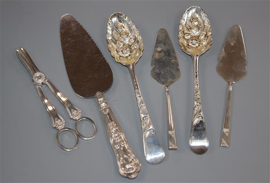 Two George III silver berry spoons, a pair of silver grape shears, a pair of small servers and a silver handled cake server.